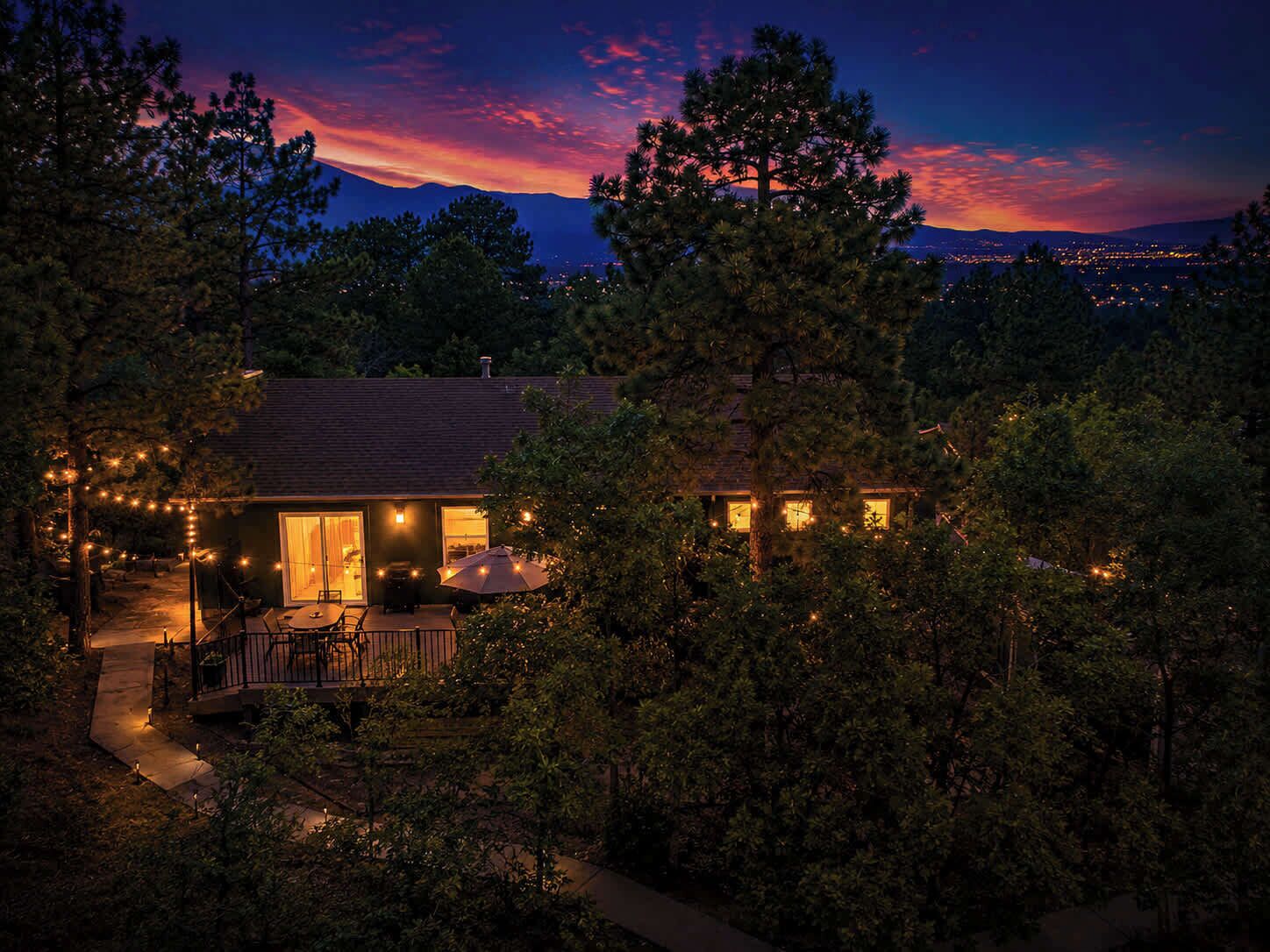 A house with a patio, outdoor lighting, and a view of the mountains at dusk.