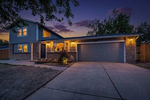 A two-story house with a garage, a covered porch, and a landscaped front yard. - 4BR Spacious Home with Deck, BBQ,Fire Pit,Sleeps 8 (Arvada)
