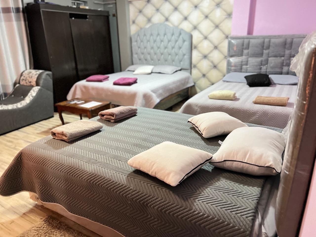 Une chambre d’hôtel avec deux lits, chacun doté d’une tête de lit au design différent, et un coin salon avec un canapé et un fauteuil.