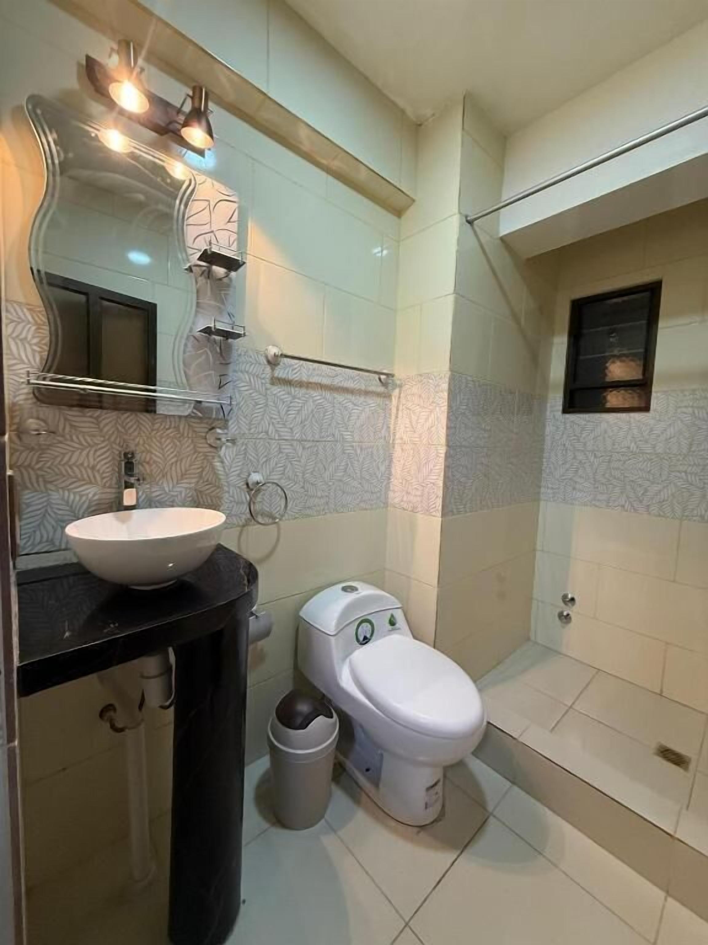 Un baño con lavamanos, inodoro y ducha blancos.