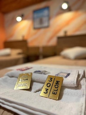 A hotel room with a bed, a towel, and a gold tag with the number 303. - Hotel Elom (Uyuni)