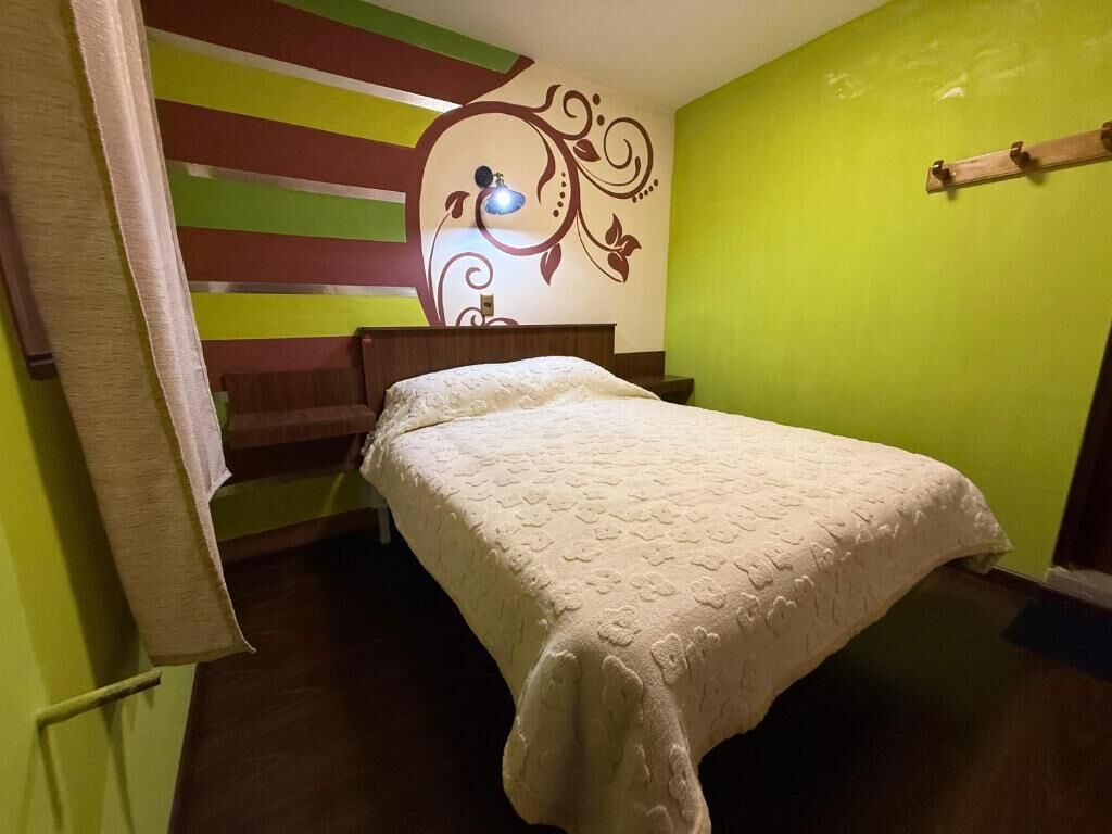 A bedroom with a bed, a wall with a decorative design, and a wooden headboard.