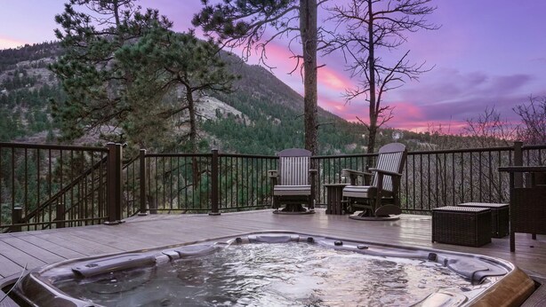 Un bain à remous sur une terrasse, avec des chaises et une vue sur les montagnes.