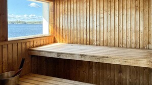 A wooden cabin with a bench by a window overlooking a lake. - Beautiful home in Vallvik with sauna (Vallvik)