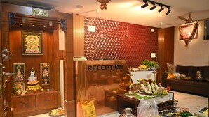 A reception area with a wooden reception desk, a wall-mounted sign, and a reception counter. - SANDALCITY HAVEN (Sathyamangalam)