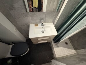 A bathroom with a white sink, a black toilet, and a shower area. - APPARTEMENT SAINT CLAIR (LE LAVANDOU)