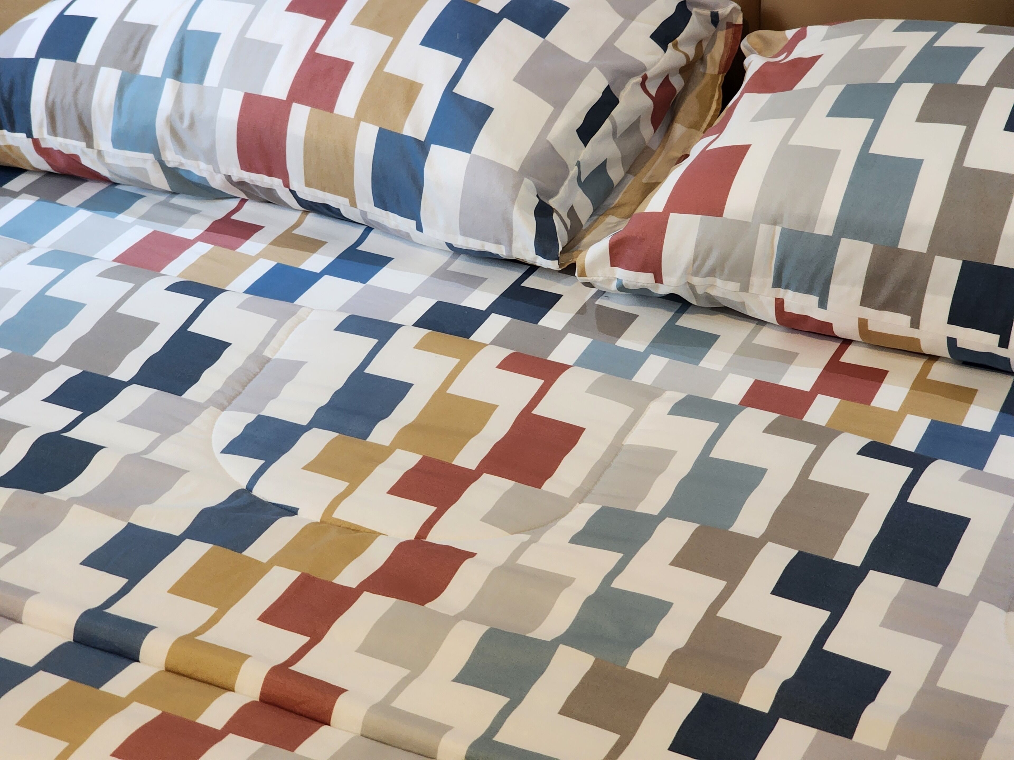 A bed with a patterned bedspread and pillows.