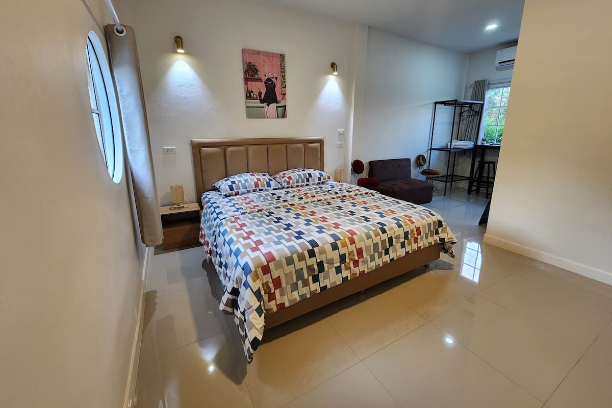 Un dormitorio con una cama, lámparas de noche, una silla, una mesita y una ventana.