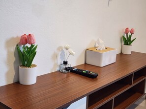 Una consola de madera con plantas en macetas, un control remoto y una caja de pañuelos.