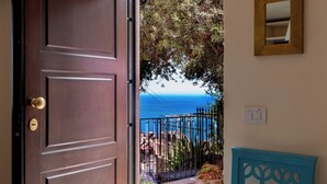 An open door leading to a balcony with a view of the sea, a blue chair, and a potted plant. - CORTE DELL'ULIVO| Sea View & Private Parking in Taormina Holiday Home (CAV) (Taormina)