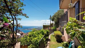 A garden with a view of the sea, a staircase, and a building with a balcony. - CORTE DELL'ULIVO| Sea View & Private Parking in Taormina Holiday Home (CAV) (Taormina)
