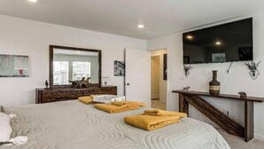 A bedroom with a bed, a dresser, a mirror, and a TV. - Spacious 4BR Home Near Denver & DIA (Thornton)