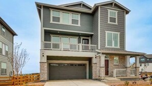 A two-story residential building with a garage, a balcony, and a stone facade. - Spacious 4BR Home Near Denver & DIA (Thornton)