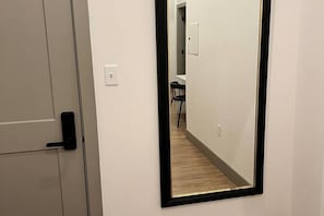 A hallway with a door on the left and a mirror on the right. - Brick & Bed/Walk to Arch/Historic Riverfront Loft, T301 (St. Louis)