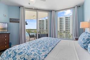 A hotel room with a large bed, a TV, a desk, and a balcony with a pool view. - Gulf views ~ Updated unit ~ Beach access ~ Pool, Hot tub, Tennis, Pickle Ball ++ (Destin)