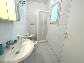 Ein Badezimmer mit einem weißen Waschbecken, einer Toilette und einer Dusche.