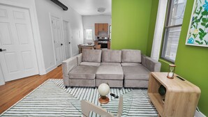 Ein Wohnzimmer mit einem Ecksofa, einem Globus, einem Holztisch und einem Haustierbett.