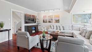 Uma sala de estar moderna com sofá, poltronas, mesa de centro e televisão.