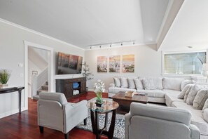 Ein modernes Wohnzimmer mit einer Couch, Sesseln, einem Couchtisch und einem Fernseher.