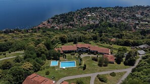 Eine Vogelperspektive auf ein Küstenanwesen mit Schwimmbad, einem großen Gebäude und einer umliegenden Landschaft.