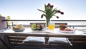 Ein Tisch mit Frühstücksangeboten, einer Blumenvase und Blick auf das Meer.