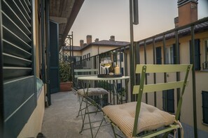 A balcony with a table, chairs, a bottle of wine, and a candle. - Corte Cavour in the City Center (Gallarate)