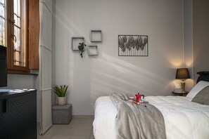 A bedroom with a bed, bedside table, lamp, and wall art. - Bianca in the Heart of the City (Somma Lombardo)