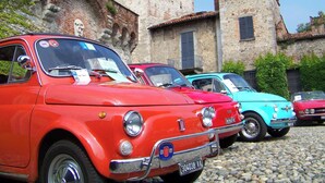 Vintage cars parked in front of a historic building with stone walls and a tower. - Bianca in the Heart of the City (Somma Lombardo)