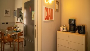 A kitchen with a refrigerator, a coffee machine, and a neon sign that reads 'Coffee'. - Bianca in the Heart of the City (Somma Lombardo)