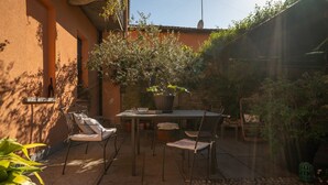 An outdoor patio with a table and chairs, surrounded by plants and a stone wall. - Bianca in the Heart of the City (Somma Lombardo)