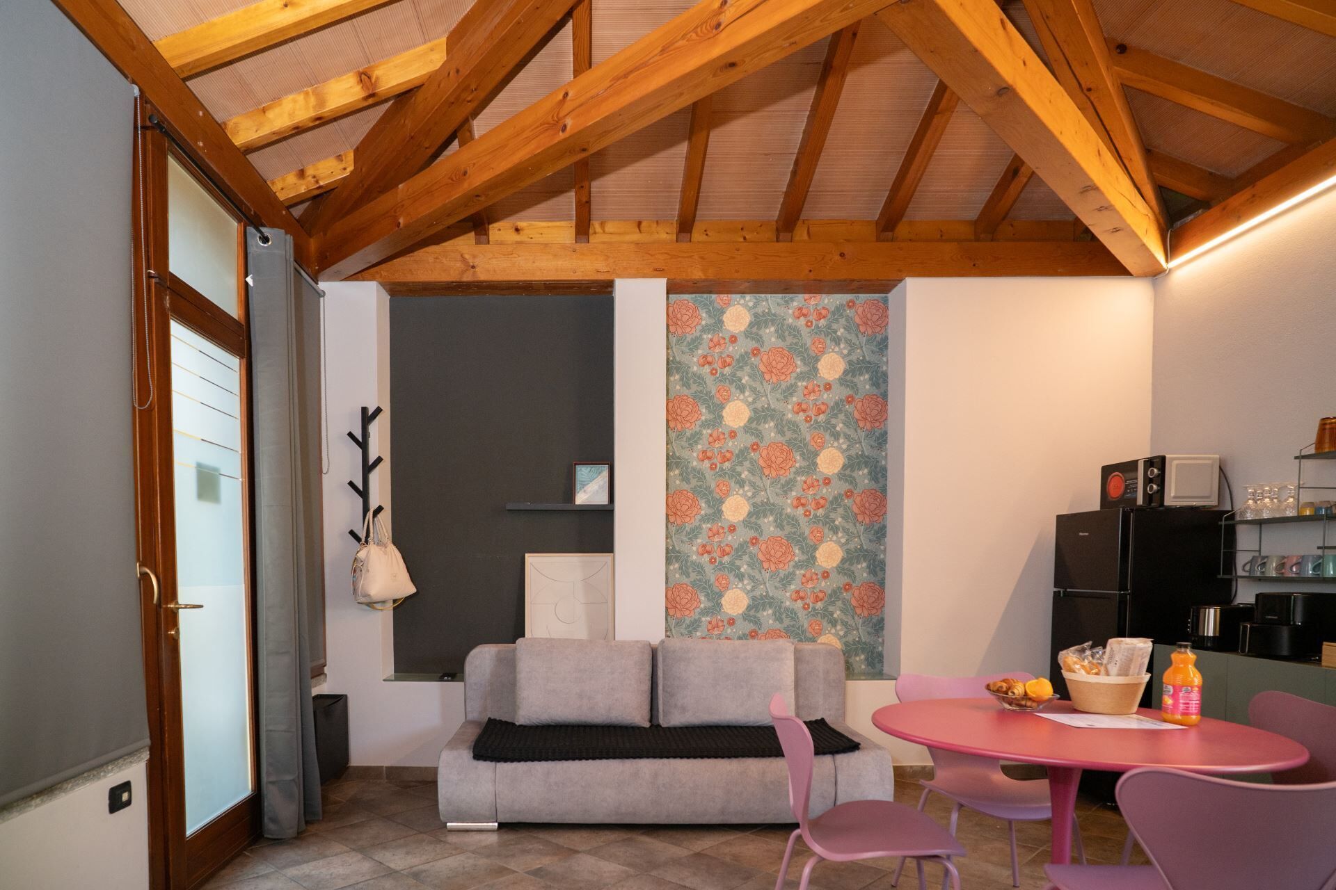 Una sala de estar acogedora con un sofá, una mesa de comedor con sillas, una zona de cocina con electrodomésticos y una pared decorativa.
