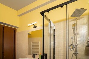 Een badkamer met een douche, wastafel, handdoekhouder en spiegel.