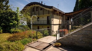 A two-story house with a curved roof, a balcony, and a staircase leading to the upper floor. - Da Gregorio: The Lake View Belvedere with Pools (Gignese)