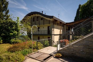A two-story house with a curved roof, a balcony, and a staircase leading to the upper floor. - Da Gregorio: The Lake View Belvedere with Pools (Gignese)