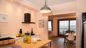 A modern kitchen with a wooden countertop, a hanging light fixture, and a view of a dining area with a table set for two. - Da Gregorio: The Lake View Belvedere with Pools (Gignese)