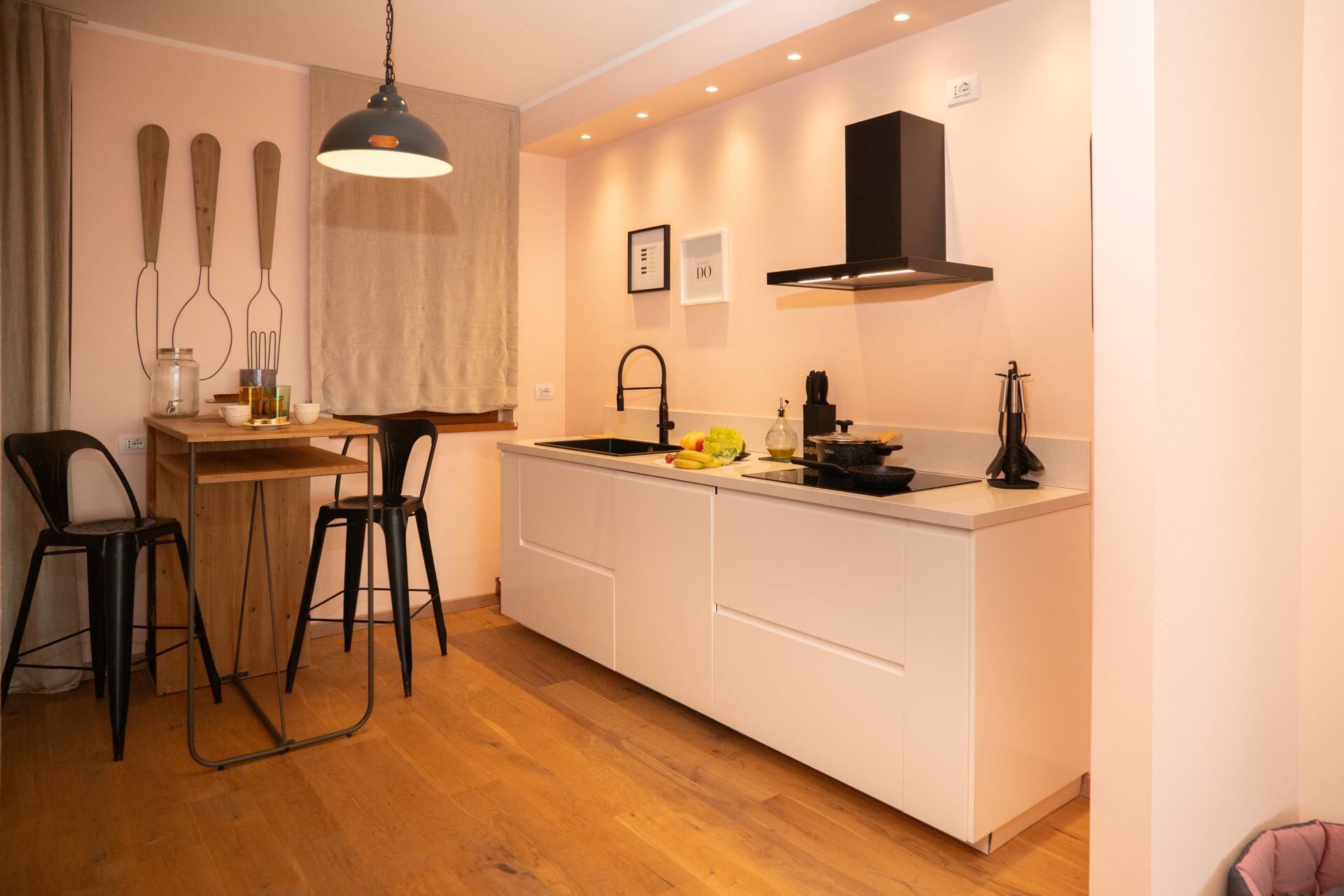 A modern kitchen with white cabinetry, a black faucet, and a hanging light fixture.