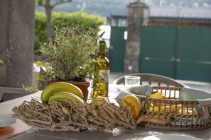Ein Tisch mit einer Topfpflanze, einer Flasche, einem Korb voller Zitronen und einem Teller mit Bananen.