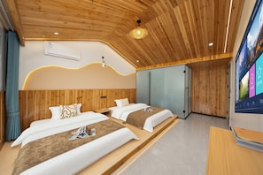 A modern hotel room with wooden ceiling, two beds, a large flat-screen TV, and a built-in wardrobe.
