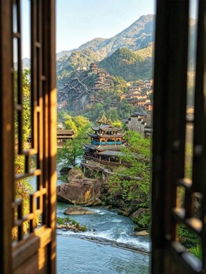 A traditional Chinese building with multiple tiers, surrounded by lush greenery and a river.