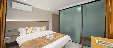 Una habitación de hotel moderna con una cama, mesita de noche y puerta corrediza de vidrio que da a un balcón.