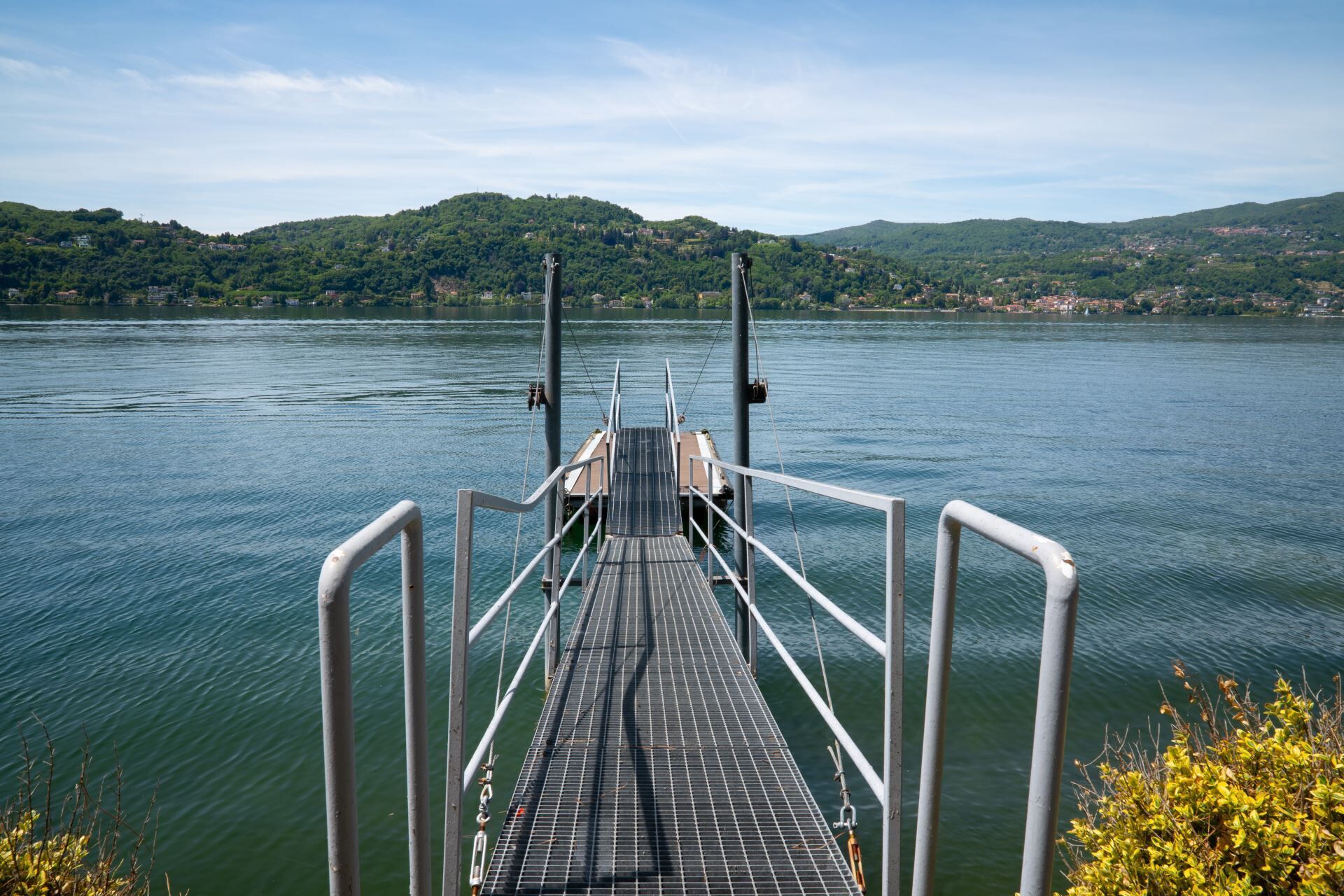 Un muelle que se adentra en un lago, con un paisaje montañoso al fondo.