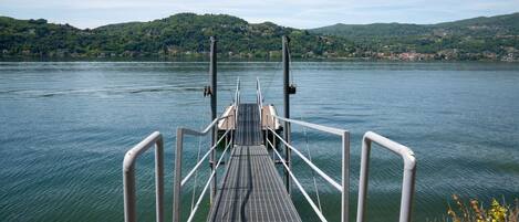 Un muelle que se adentra en un lago, con un paisaje montañoso al fondo.