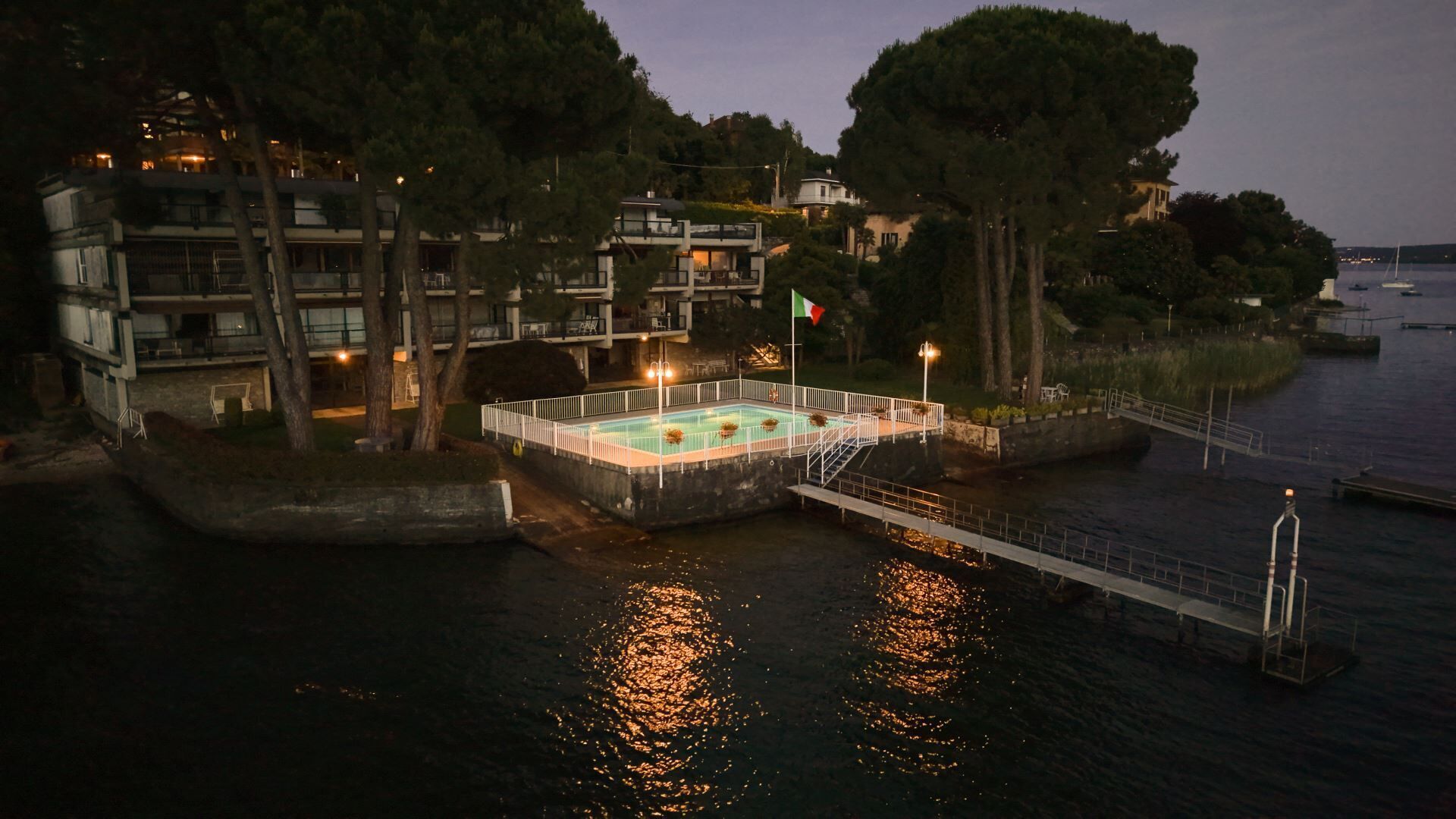 A waterfront property with a swimming pool, a bridge, and buildings in the background.