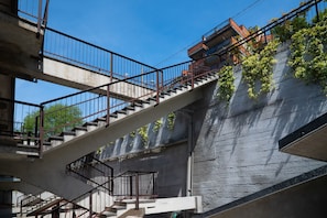 A staircase with metal railings leading to a building with a concrete exterior and some greenery on the wall. - Henriette Apt Terrace, Lake Access (Angera)