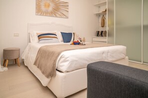 Ein modernes Schlafzimmer mit Bett, Nachttisch und Sessel.