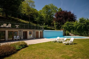 Ein modernes Gebäude mit Schwimmbad, Außenbereich mit Sitzgelegenheiten und einer Rasenfläche.