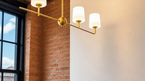 Un plafond avec des poutres en bois apparentes et un luminaire suspendu doté de trois ampoules.