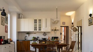 Een moderne keuken met witte kasten, een eetgedeelte met een glazen tafel, en een woonkamer met een bank en salontafel.
