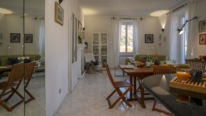 Een ruime woonkamer met een eettafel, stoelen, een bank en een open haard.