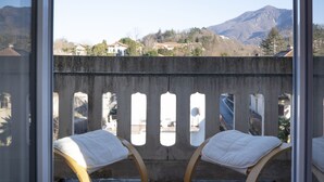 Een balkon met twee schommelstoelen, uitzicht op bergen en een heldere lucht.
